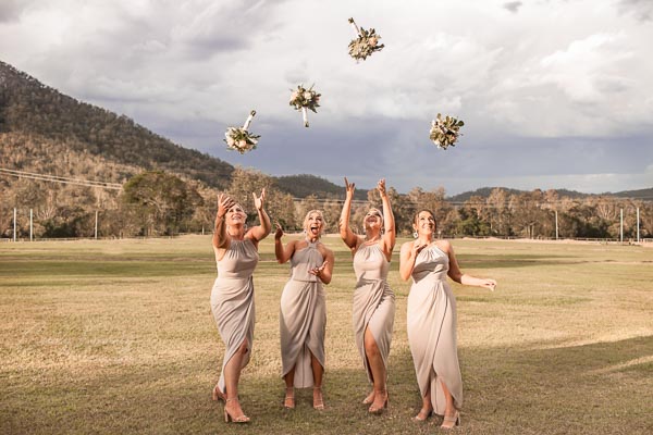 4 bridesmaids throwing bouquets up in air