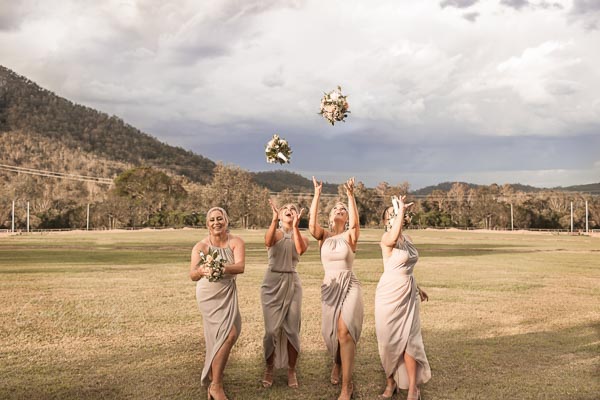 4 bridesmaids throwing bouquets up in air