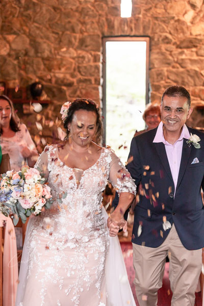 Bride & groom leaving ceremony in shower of confetti 