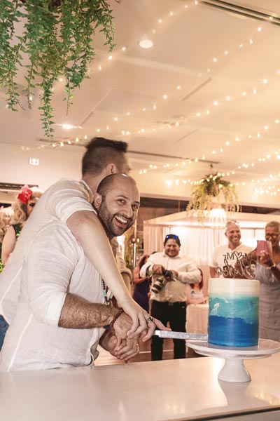 Gay wedding couple cutting cake