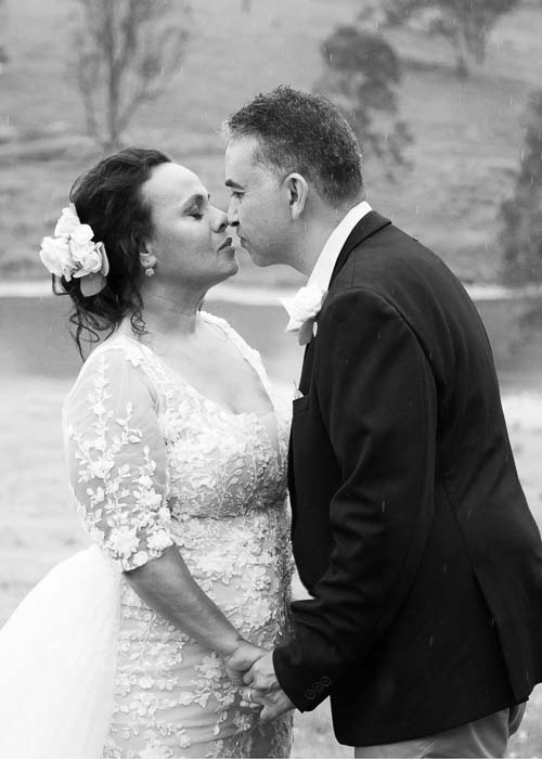 Black & white of couple kissing in rain